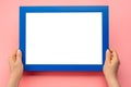 Holding frame mockup. Photo Mockup. Woman hands hold blue frame on pink background. For frames and posters design. Frame size A4. Royalty Free Stock Photo