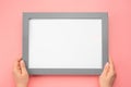 Holding frame mockup. Photo Mockup. Woman hands hold gray frame on pink wall background. Frame size A4. blank photo frame border Royalty Free Stock Photo