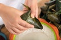 Holding a freshly wrapped zongzi in hand