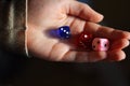 Holding gambling dices. Throwing three Six-seided dice in female`s hand. Teenager is rolling three dice. Dark background.