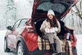 Holding gift box. Beautiful young woman is outdoors near her red automobile at winter time Royalty Free Stock Photo