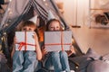 Holding gift boxes. Conception of presents and holidays. Two little girls is in the tent in domestic room together Royalty Free Stock Photo