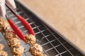 Holding grains cookies with serving tongs on waxed sheet