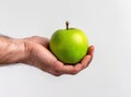 Holding a green apple on a white background, a close up view of a male hand with a fresh orga