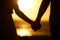 Holding hands, couple and silhouette on beach at sunset for vacation or holiday outdoor. Behind man and woman in nature Royalty Free Stock Photo