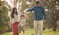 Holding hands, park and parents play with kid in nature for fun, bonding and relax together. Happy family, childhood and Royalty Free Stock Photo