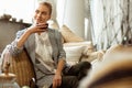 Beaming blonde woman in black pants resting on a sofa