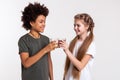 Cheerful appealing kids clinking glasses filled with sweet drinks