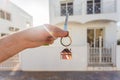 Holding house keys on house shaped keychain closeup in front of a new home. Concept of real estate Royalty Free Stock Photo