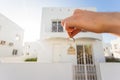 Holding house keys on house shaped keychain closeup in front of a new home. Concept of real estate Royalty Free Stock Photo