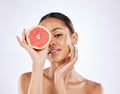 Holding the key to clarity in my hand. a beautiful young woman covering her eye with a grapefruit against a studio Royalty Free Stock Photo