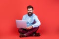 Holding laptop computer. Smiling handsome bearded man worker laptop. Happy young man sitting on the floor with and using Royalty Free Stock Photo