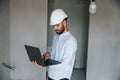 Holding laptop in hands. The man is making repairs in the apartment