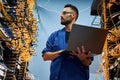 Holding laptop. Young man is working with internet equipment and wires in server room Royalty Free Stock Photo