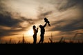 Holding little baby in hands. Silhouettes of father and mother that are outdoors against sunset dramatic sky in the field Royalty Free Stock Photo