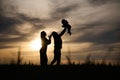 Holding little baby in hands. Silhouettes of father and mother that are outdoors against sunset dramatic sky in the field Royalty Free Stock Photo