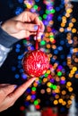 Holding Merry Christmas bauble decoration isolated on background with blurred lights. December season, Christmas composition Royalty Free Stock Photo