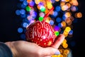 Holding Merry Christmas bauble decoration isolated on background with blurred lights. December season, Christmas composition Royalty Free Stock Photo