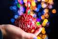 Holding Merry Christmas bauble decoration isolated on background with blurred lights. December season, Christmas composition Royalty Free Stock Photo