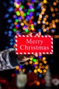 Holding Merry Christmas sign isolated on background with blurred lights. December season, Christmas composition Royalty Free Stock Photo