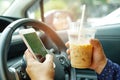 Holding mobile phone with ice coffee in car to communication with family.