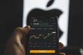 Holding mobile phone with stock market charts of Apple company shares