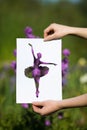 Holding papercut miniature ballerina over blooming flowers