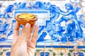 holding Pastel de nata in Porto Portugal in front of beautiful white blue azulejo tiles