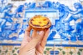 holding Pastel de nata in Porto Portugal in front of beautiful white blue azulejo tiles