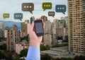 Holding phone and Chat bubble icons over city Royalty Free Stock Photo