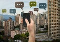 Holding phone and Chat bubble icons over city Royalty Free Stock Photo