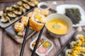 Holding a piece of California Maki with chopsticks, above a selection of various sushi rolls Royalty Free Stock Photo