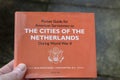 Holding A Pocket Guide For American Servicemen Of The Cities Of The Netherlands During World War II At Amsterdam The Netherlands