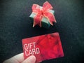 Holding a red gift card against a gift on black background.