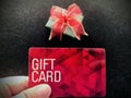 Holding red gift card with green gift box in front, on black background. Royalty Free Stock Photo