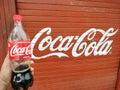 Holding a refreshing bottle of black soda cold drink outside the shop. Red colored coke is a popular carbonated coca cola. Royalty Free Stock Photo