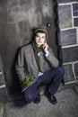 A young guy is sitting on a door way, waiting outside in New York City