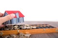 Holding a small house model, beads and scattered euro coins