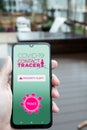 Holding smartphone with coronavirus contact tracing application mockup