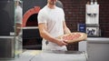 Holding in strong hands. Baker in white shirt with pizza that ready for put in the oven to cook