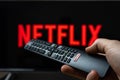 Holding TV remote controller with Netflix logo