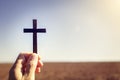 Holding up religious cross crucifix to sky and earth background