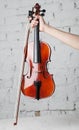 Holding violin with bow under white grand piano with brick wall background Royalty Free Stock Photo