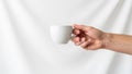 Holding a white ceramic cup by its handle against a plain white Royalty Free Stock Photo