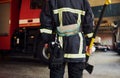 Holds axe in hands. Male firefighter in protective uniform standing near truck Royalty Free Stock Photo