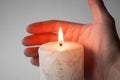 Holds hand near a burning white candle Royalty Free Stock Photo