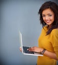 She holds the key to connectivity. Studio portrait of a young woman using a laptop against a gray background. Royalty Free Stock Photo