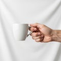 Holds a plain white ceramic mug against a smooth white background. Royalty Free Stock Photo