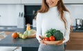 Holds plate with vegetables. Young european woman is indoors at kitchen indoors with healthy food Royalty Free Stock Photo