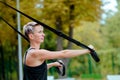 Young girl doing exercises outdoors, holds TRX loop/